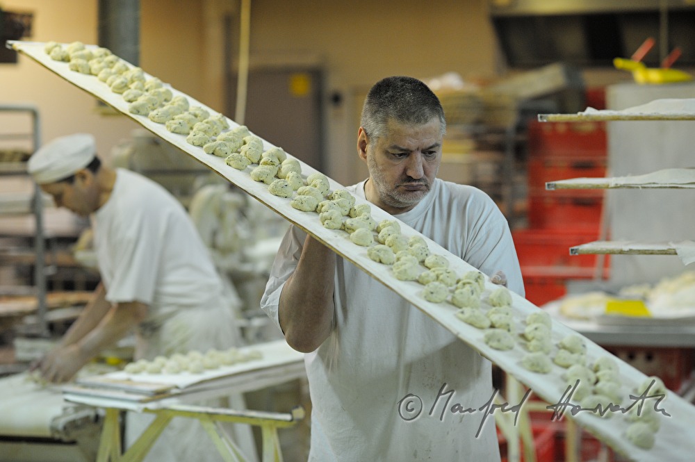 baker carries a tray with wheat dough portions