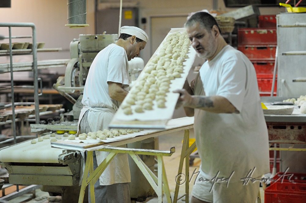 baker carries a tray with wheat dough portions