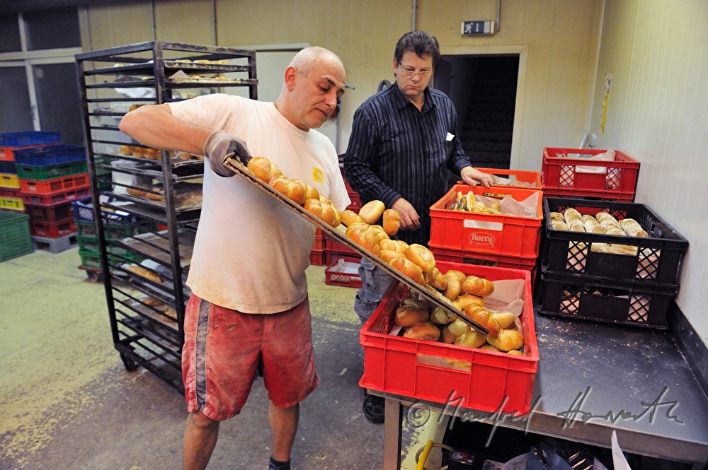 freshly baked bread rolls are being filled into baskets