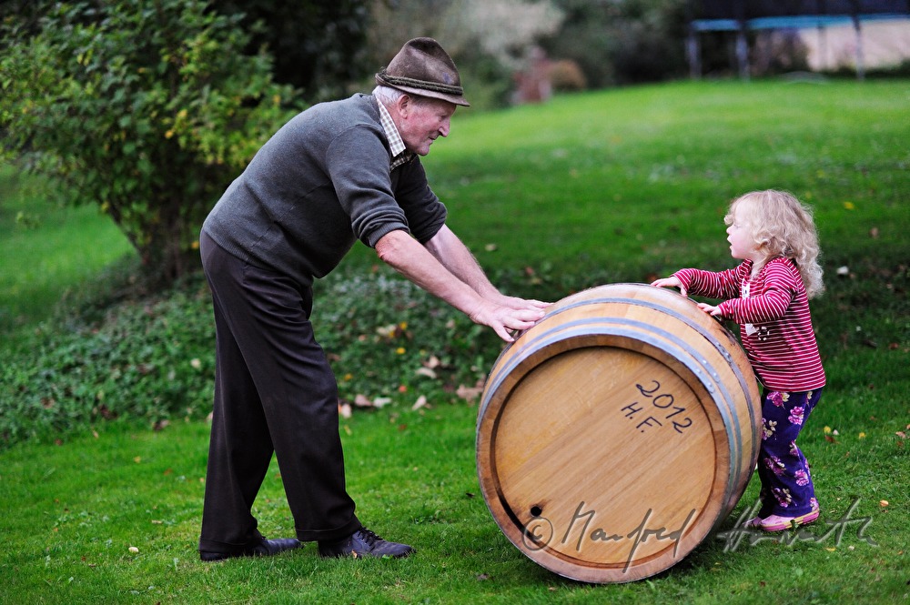must farmer with grandchild rolling a barrel