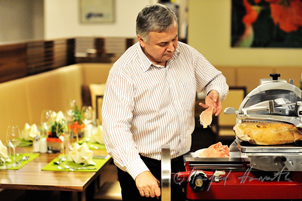 Alois Gölles slices Vulcano Ham in his restaurant