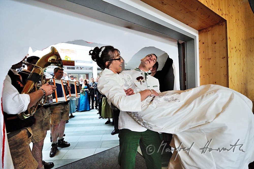 groom carries his new wife into the festivity hall