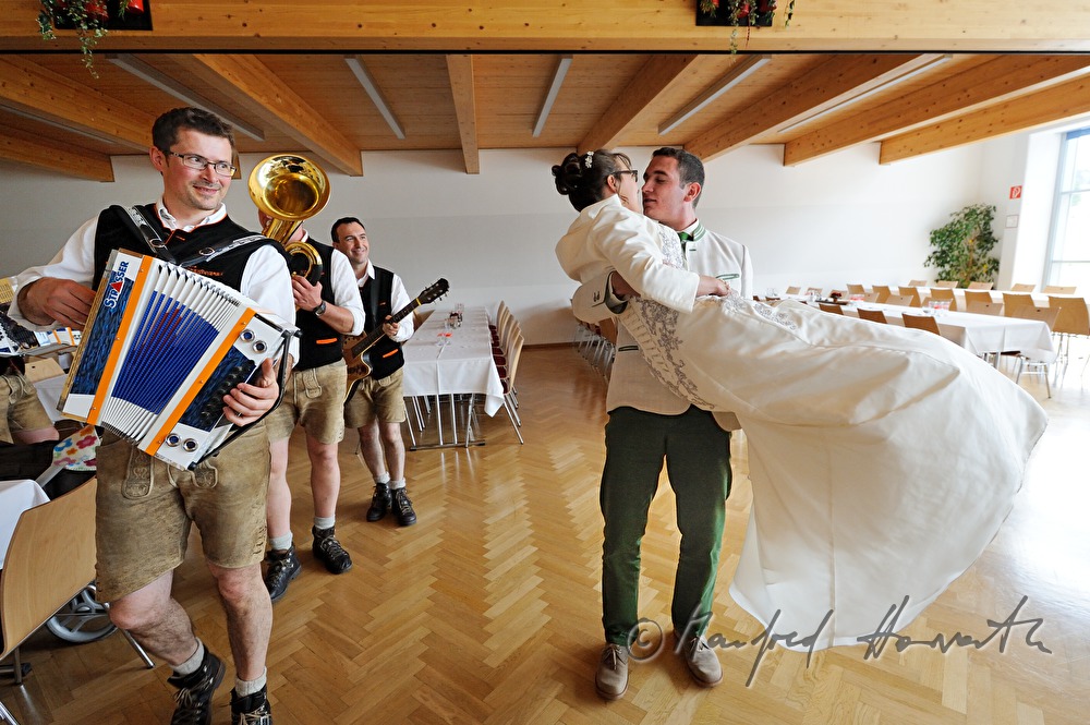 groom carries his new wife into the festivity hall