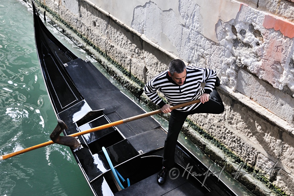 gondolier pushes off a house wall