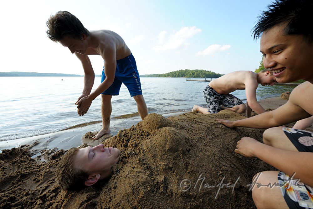 boys digging themselves in sand