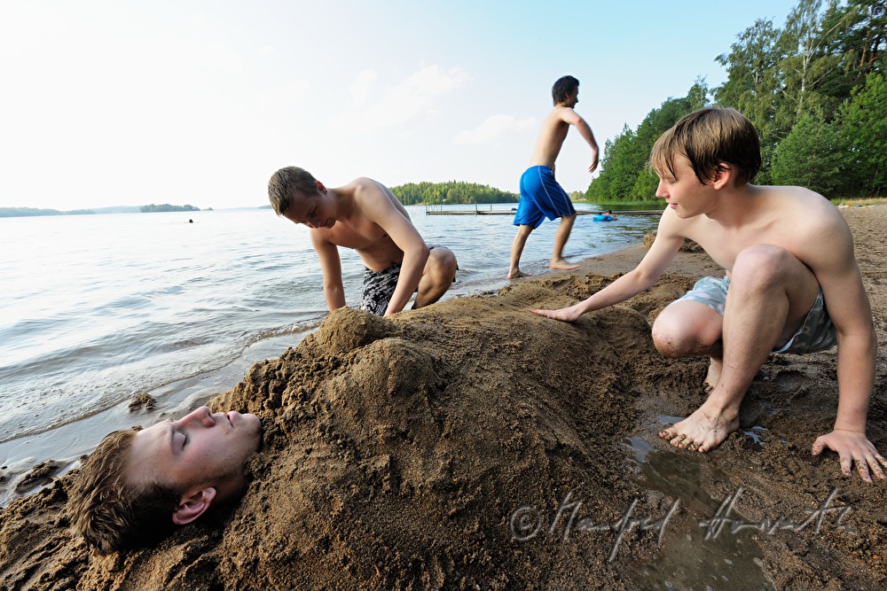 boys digging themselves in sand