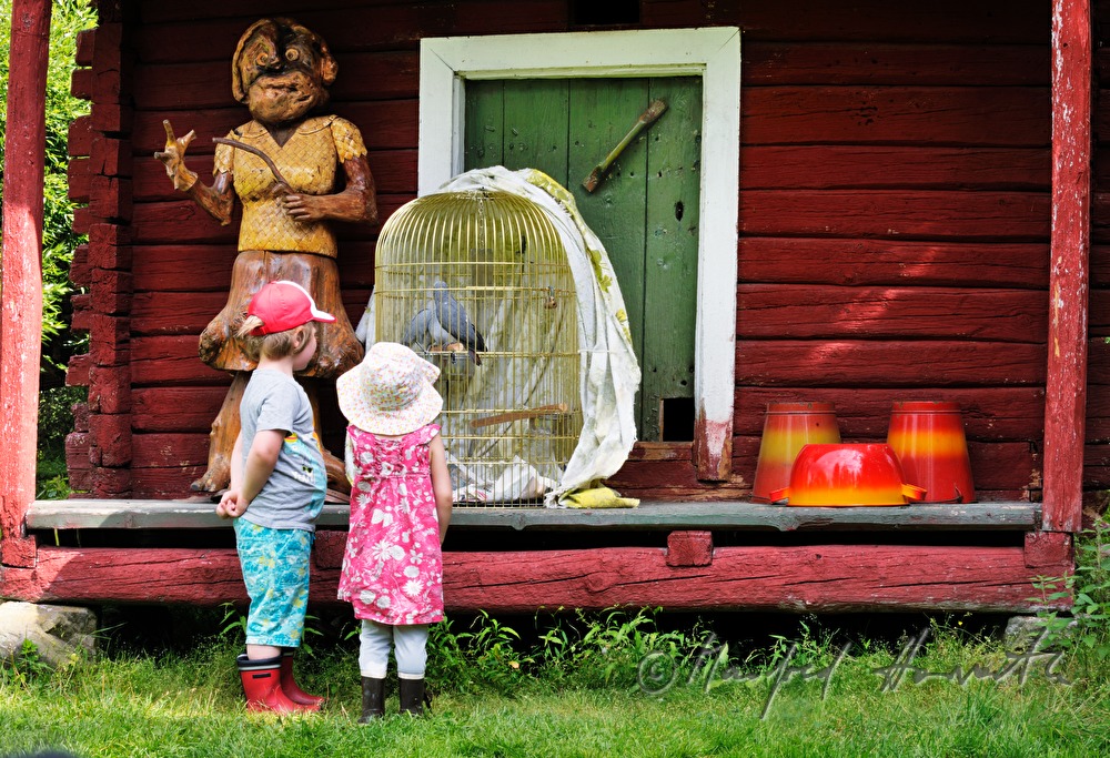 children in front of a farm house with a bird cage