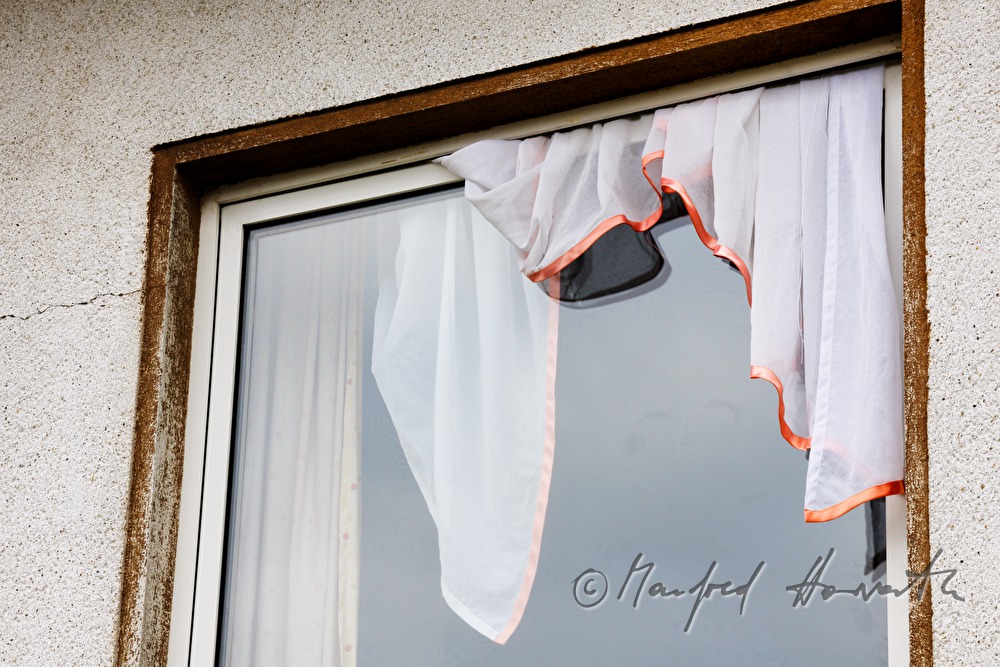 window of a farm house with jammed curtain