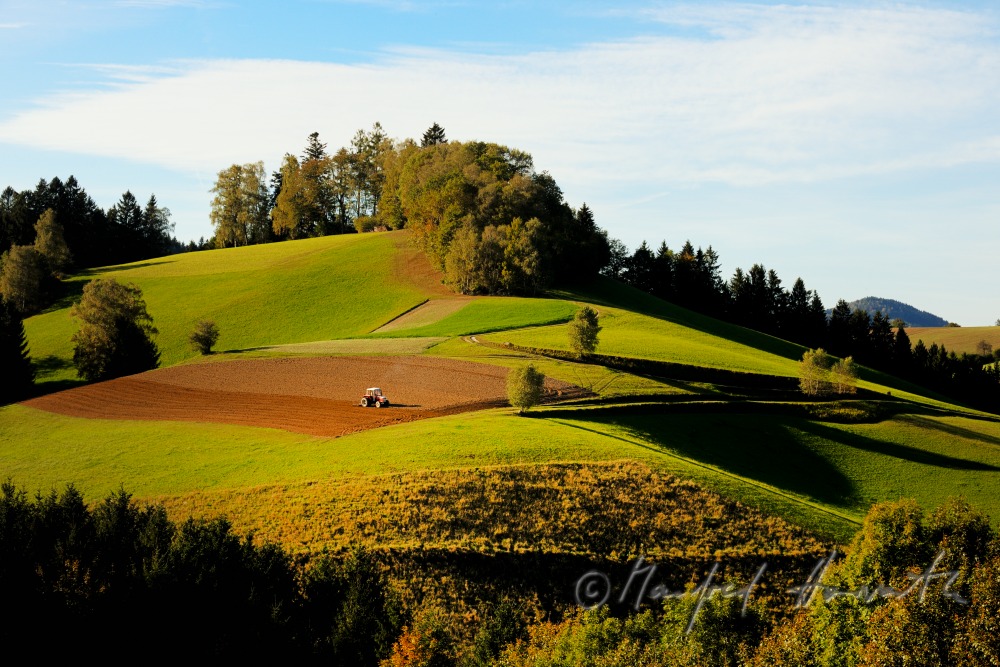 trctor in a field on a mountain ridge