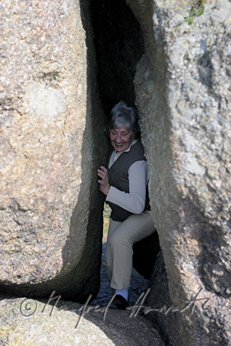 woman climbs between the two halfs of a rock