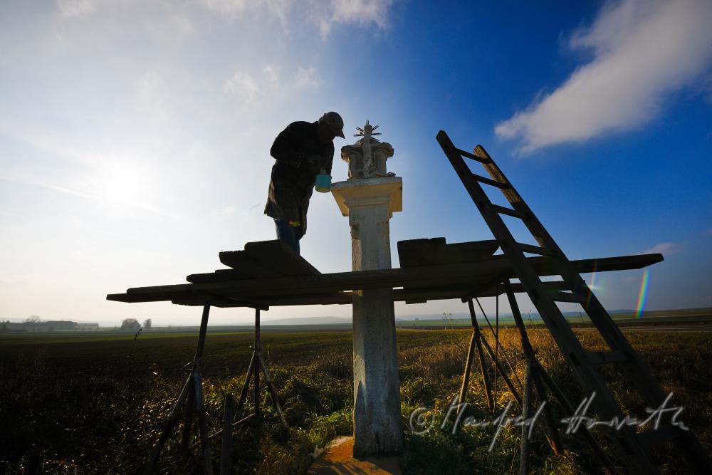conservator restoring a wayside shrine