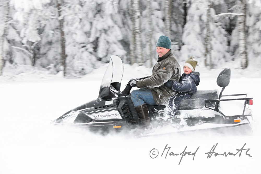 father and son ride on a snowmobile