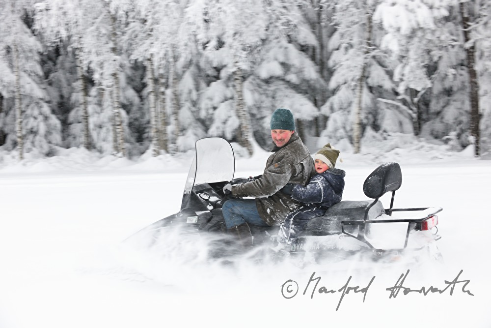 father and son ride on a snowmobile