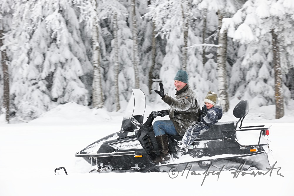 father and son ride on a snowmobile