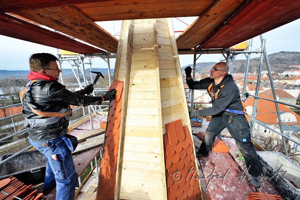 roofers work on the steeple of the church