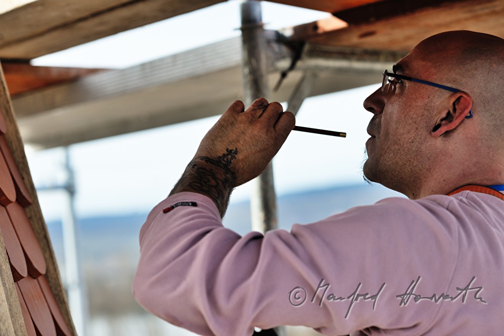 roofer works on the steeple of the church