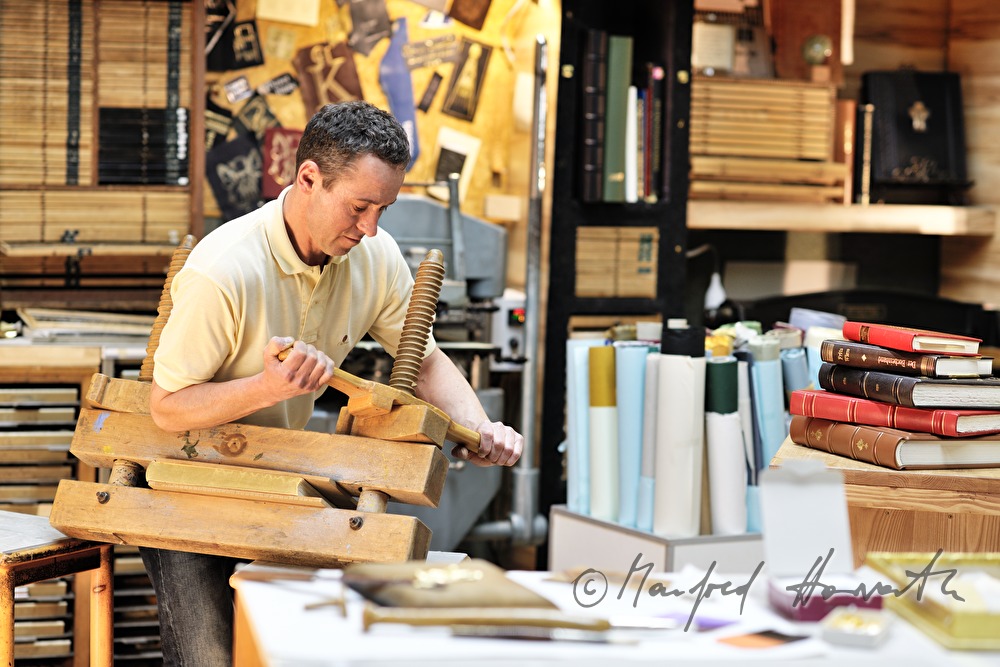 bookbinder Ernst Gstettenhofer squeezes a book with gilt edging