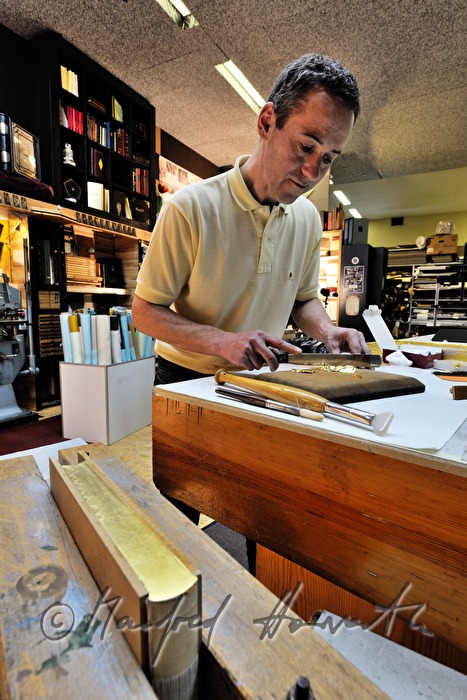 bookbinder Ernst Gstettenhofer squeezes a book with gilt edging
