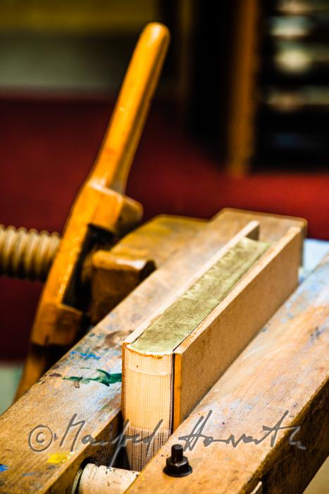 bookbinder Ernst Gstettenhofer squeezes a book with gilt edging
