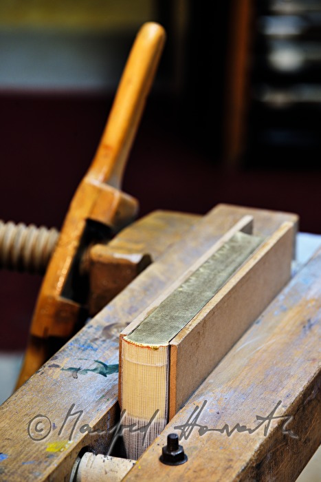 bookbinder Ernst Gstettenhofer squeezes a book with gilt edging