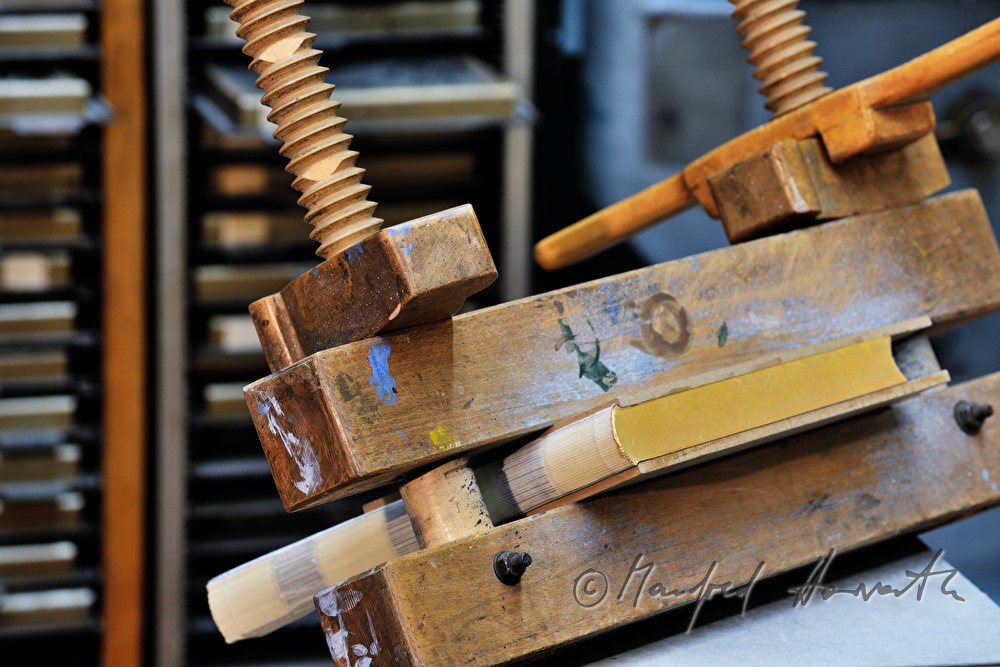 bookbinder Ernst Gstettenhofer squeezes a book with gilt edging