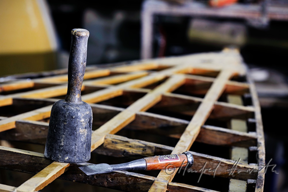 chisel and wooden hammer on a wooden sailing boat