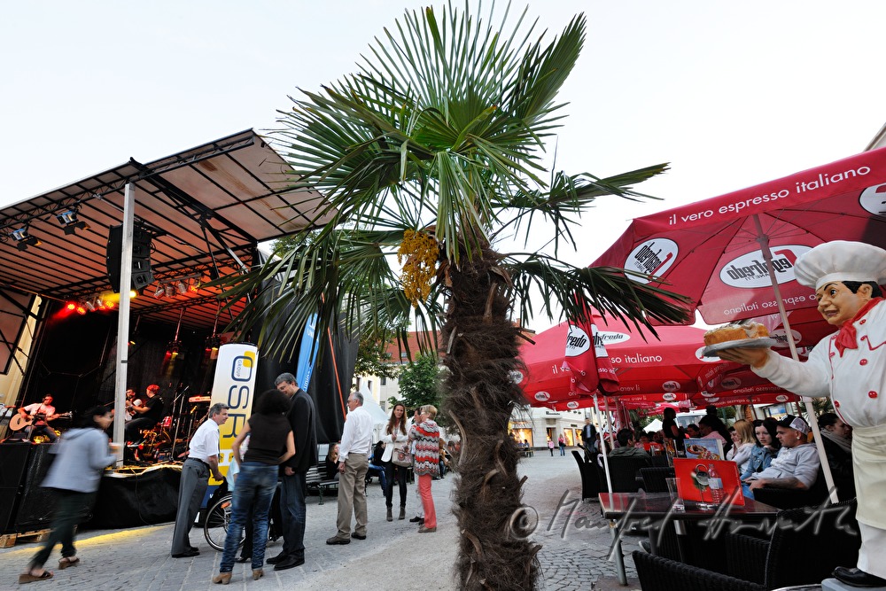 pedestrians passing the stage and street cafes