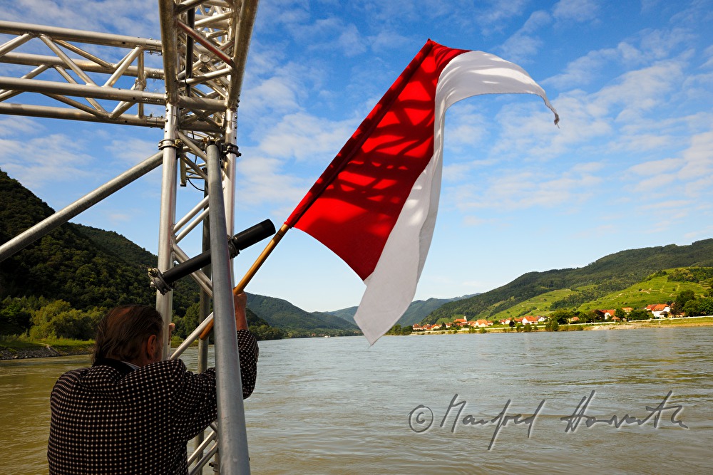 navigator of a motor boat hoists the Austrian flag