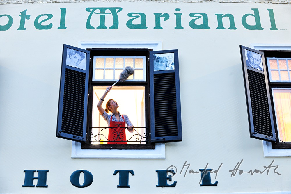 cleaning lady at work on the open window of Hotel Mariandl
