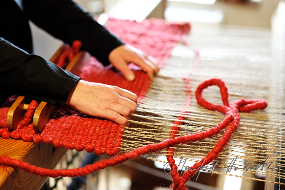 Barbara Schmidt weaves a wool carpet in her workshop