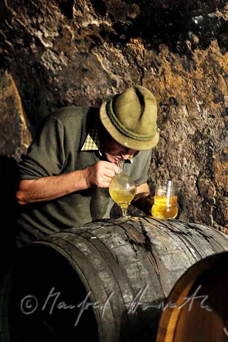 must farmer takes a tasting sample with a syphon