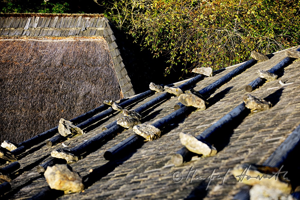 farmhouse with thached roof and stones on the shingle roof
