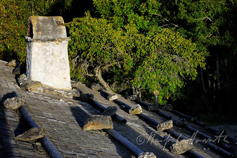 farmhouse with thached roof and stones on the shingle roof