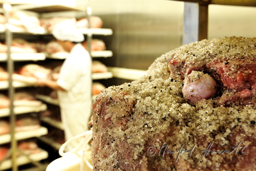 butcher checks corned legs of pork in the cooling chamber