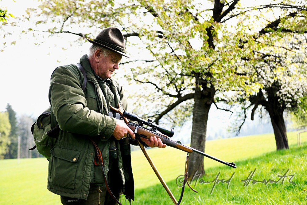 gamekeeper unlocks his long rifle in an orchard