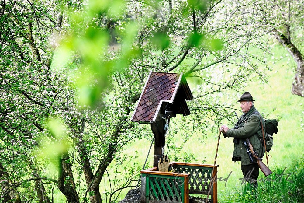gamekeeper meditates at a wayside shrine