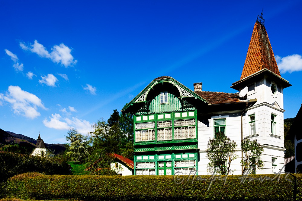 villa with wooden verandah and tower