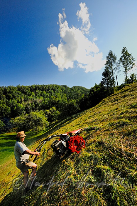 mountain farmer mowing the slope with a motor mower
