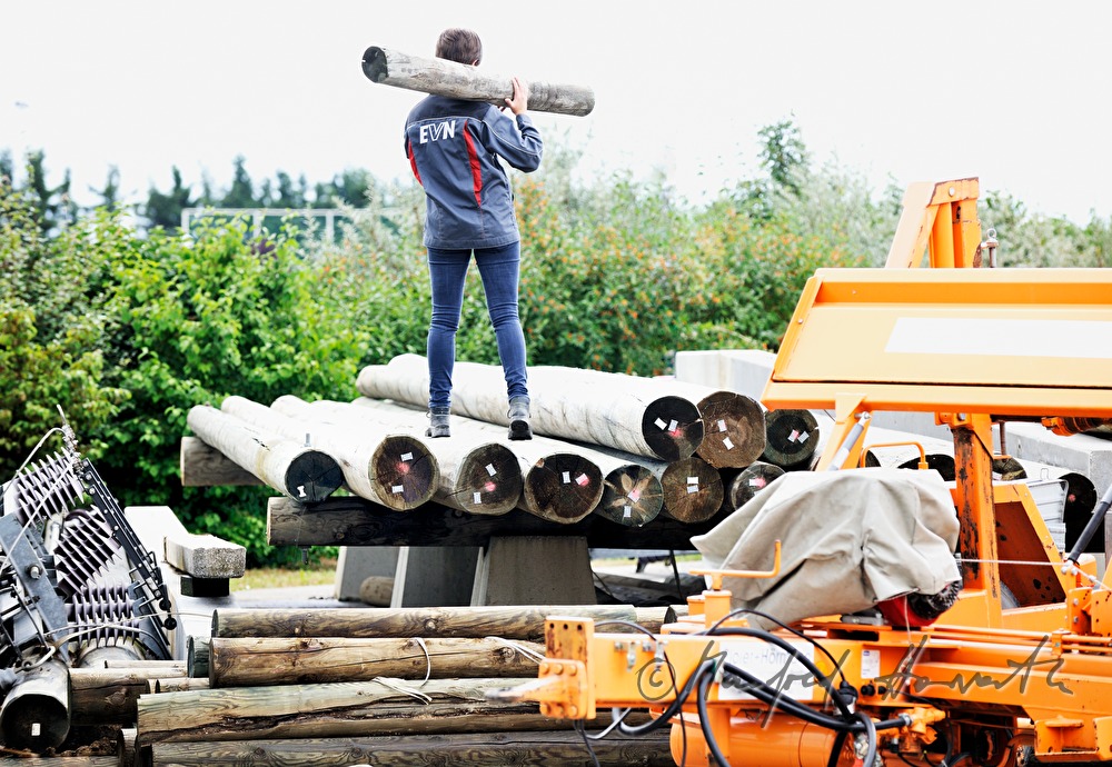 woman electrician carrying a power pole