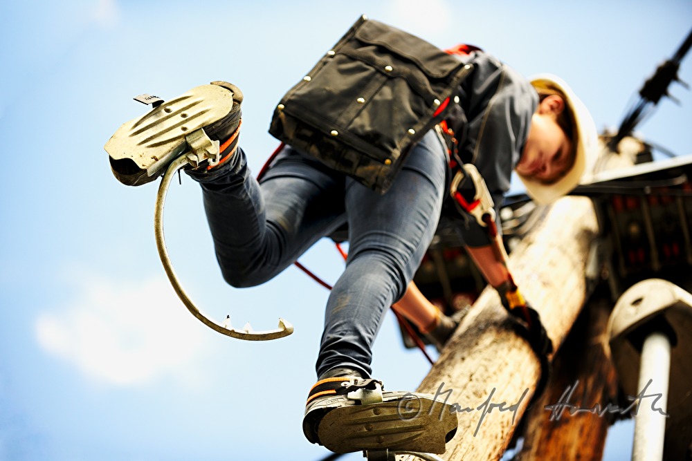 woman electrician climbing a power pole
