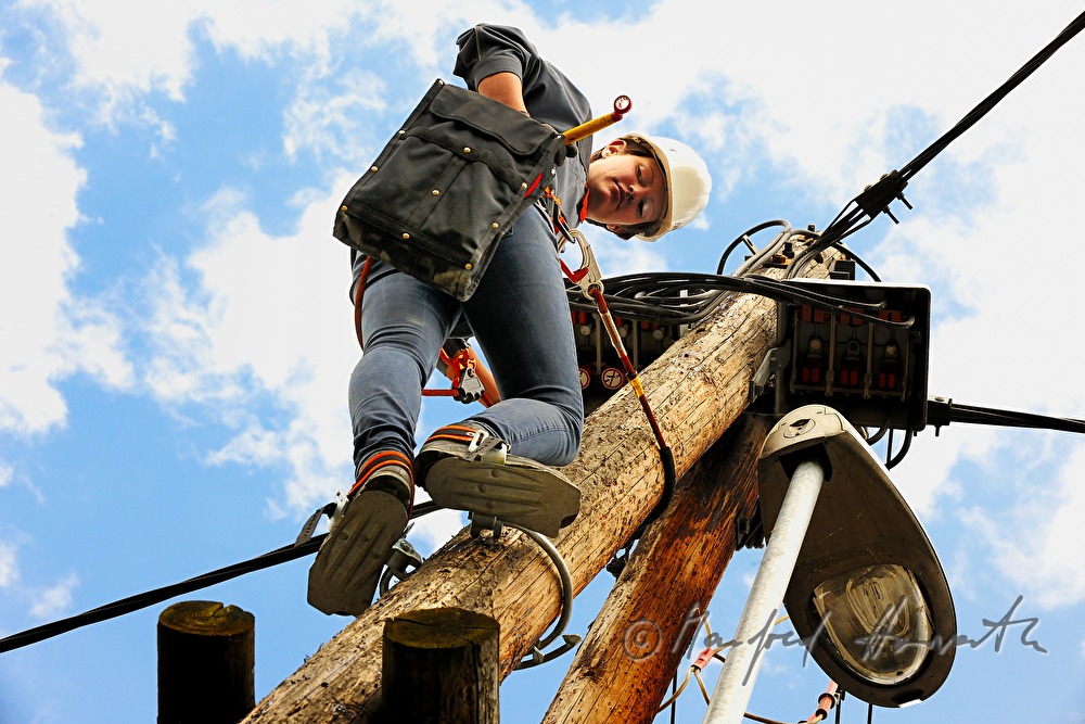 woman electrician climbing a power pole