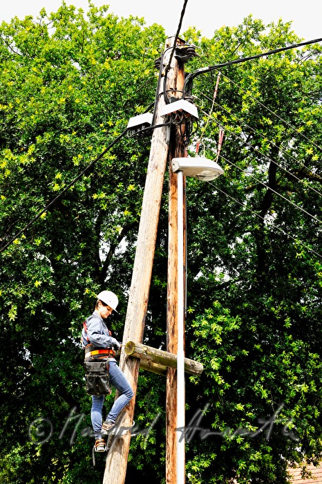 woman electrician climbing a power pole