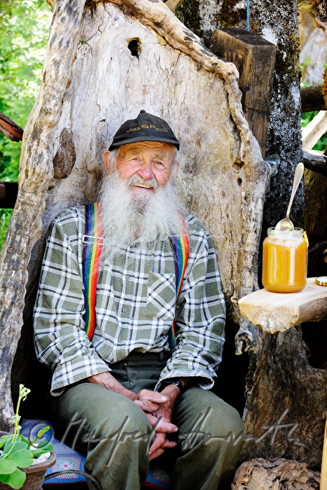 beekeeper with honey on the bench in front of his house