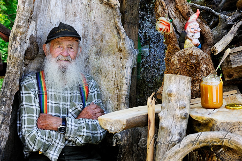 beekeeper with honey on the bench in front of his house