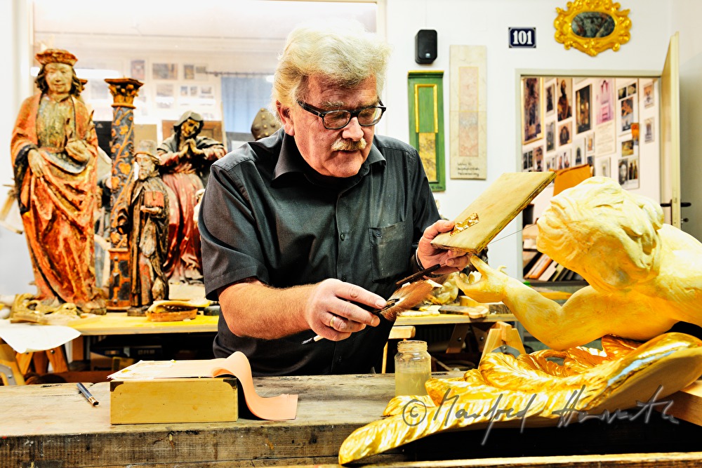 gilder gold-plating an angel from the baroque times