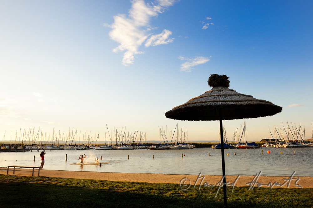 lakeside promenade with a sun umbrella made of reed