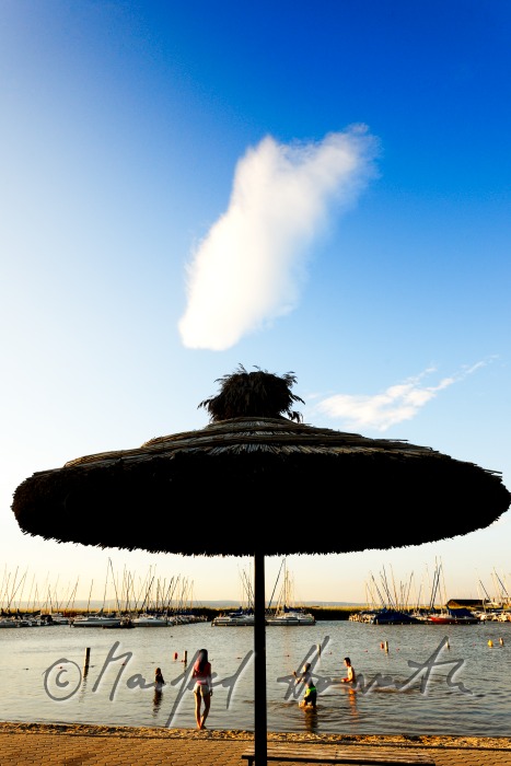 lakeside promenade with a sun umbrella made of reed