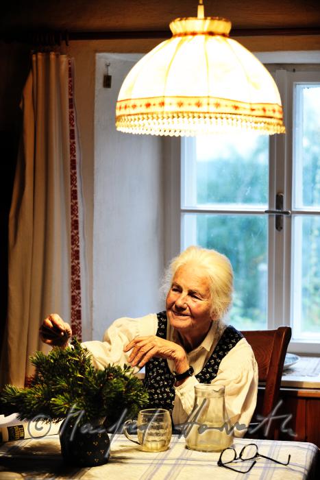 Mrs. Fuchs with a fir branch at the kitchen table