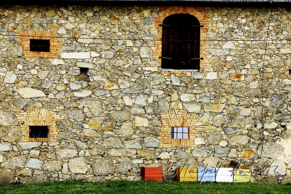 colorful beehives in front of a stone house