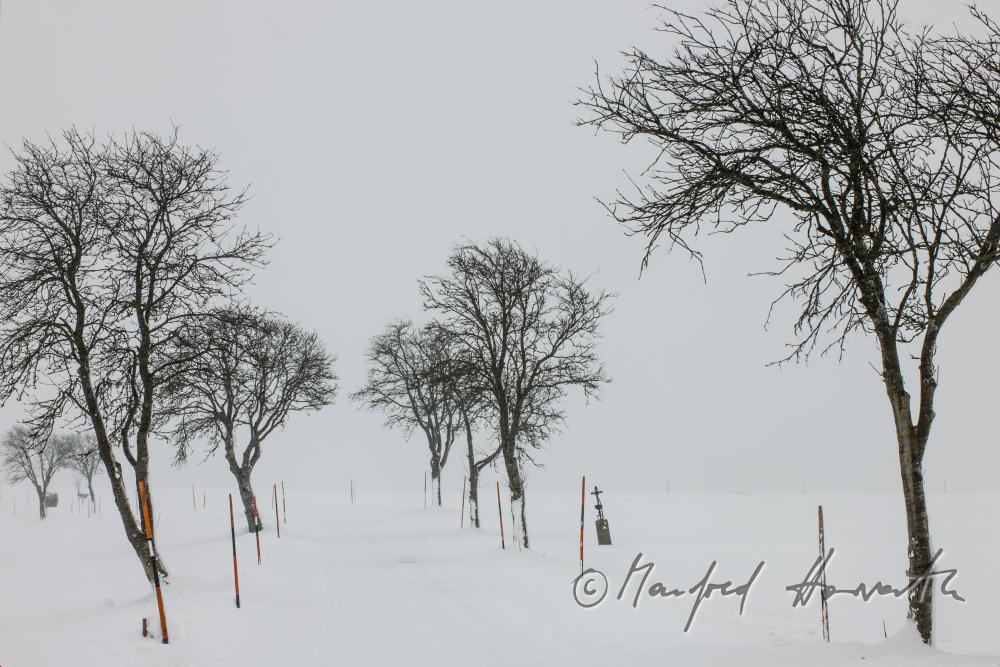 snow drift on a country road and a cross for a traffic victim